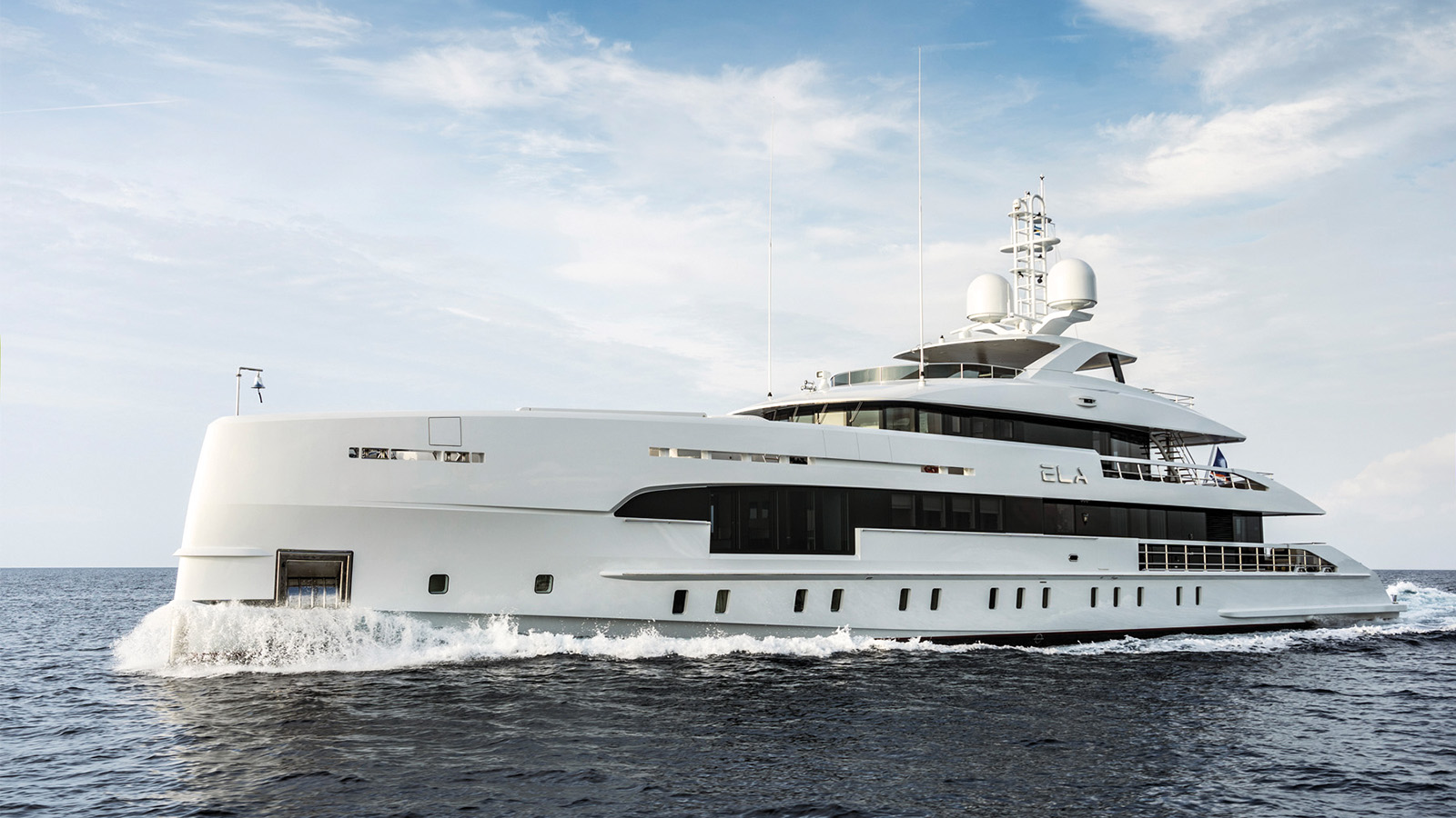 A luxurious white yacht cruising through the ocean under a clear sky, with multiple decks and modern design features.